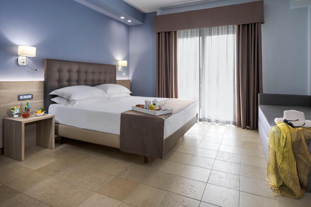 a bedroom with a large white bed and a window at Netum Hotel in Noto