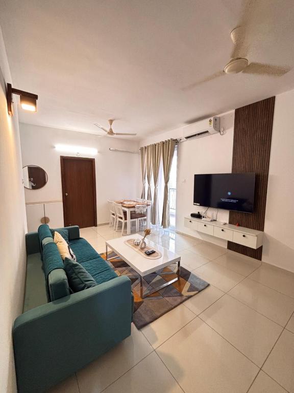 a living room with a blue couch and a tv at Pool View 3 BR Adora, Goa Amoret Homes in Chicalim
