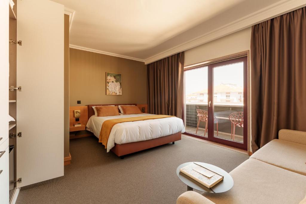 a hotel room with a bed and a balcony at Made Inn Entroncamento in Entroncamento