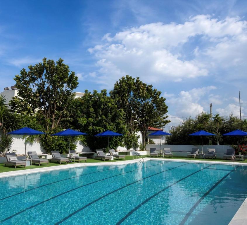 a swimming pool with chairs and umbrellas at Smart Accomodation Rhodes by GHH in Rhodes Town