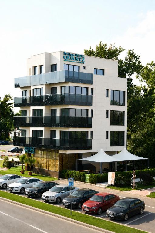 a building with cars parked in a parking lot at Quartz Boutique Hotel in Mamaia