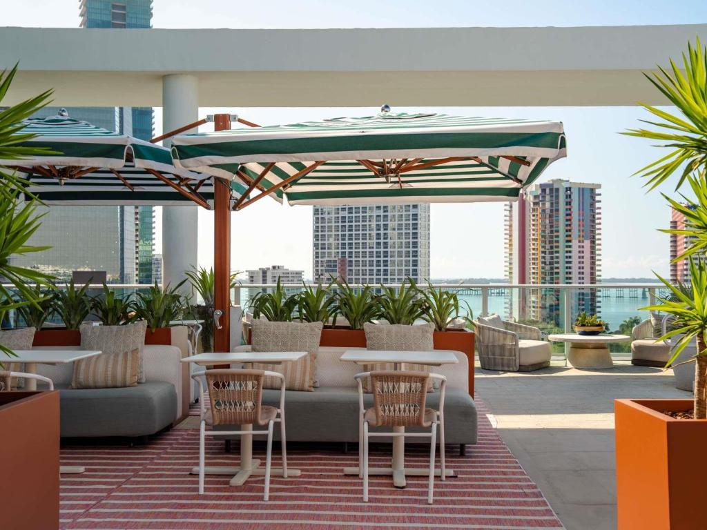 a patio with tables and chairs and an umbrella at Novotel Miami Brickell in Miami
