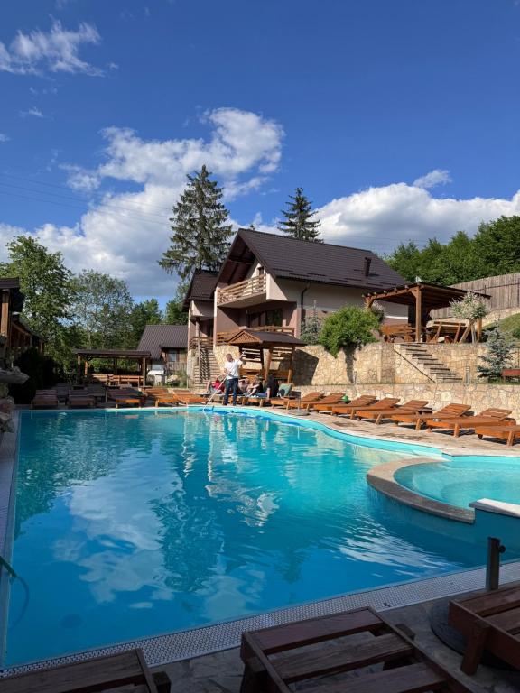 a large swimming pool with chairs and a house at Vikendica Bjelašnica II in Sarajevo