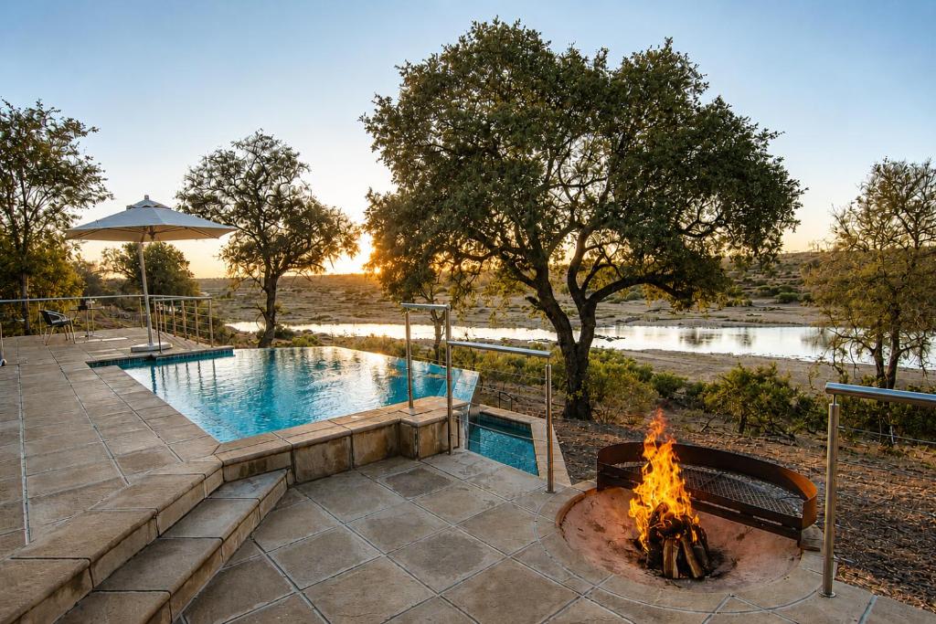 a fire pit next to a swimming pool with a fire place at LeoLapa in Hectorspruit