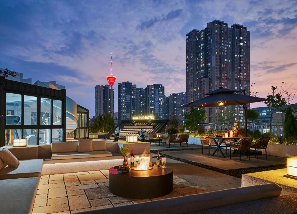 a rooftop patio with a city skyline at night at Chengdu Yunduo 云朵Hotel in Chengdu