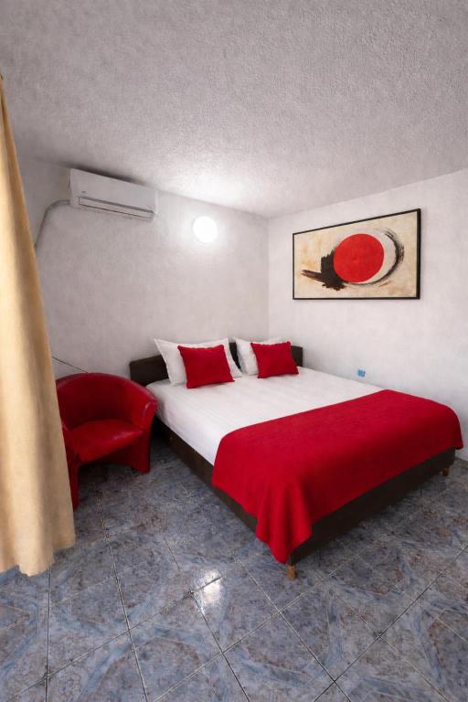 a bedroom with a large bed and a red chair at Vila Rubin in Eforie Nord