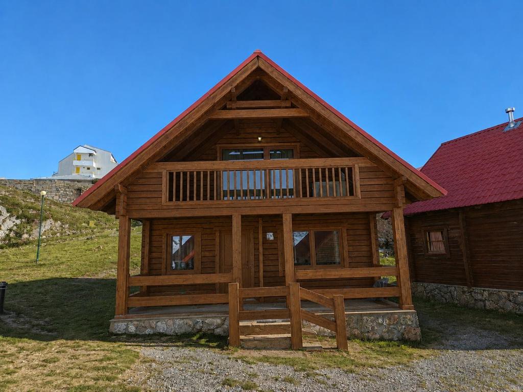 a large wooden cabin with a red roof at Chalet O Refúgio 1 in Penhas da Saúde