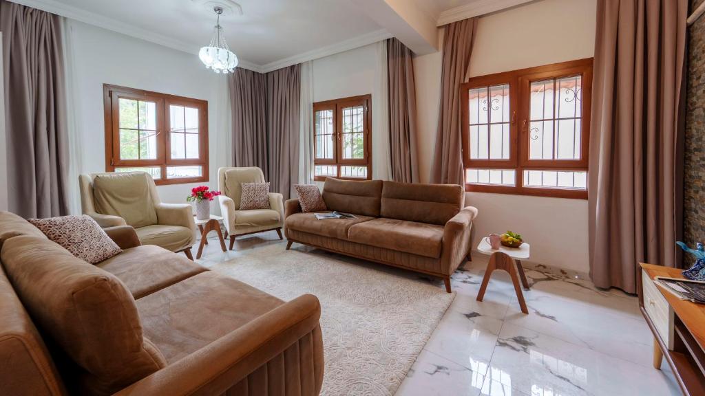 a living room with a couch and chairs and windows at Flower Apart 2 - Flower Hotel Patara in Gelemiş