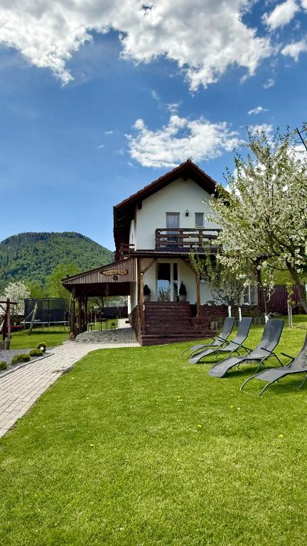 a house with lawn chairs in front of a house at Casa de sub Horă in Zărneşti