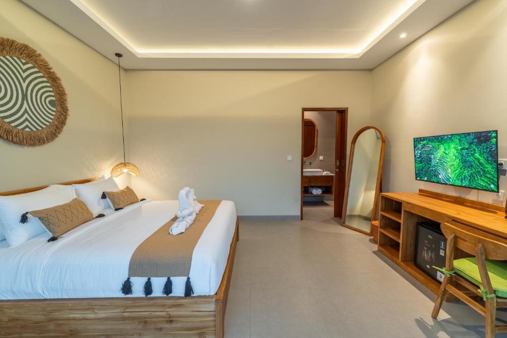 a bedroom with a bed and a flat screen tv at Pondok Tis Bisma in Ubud