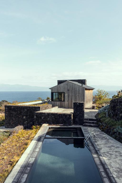 a house with a swimming pool in front of the ocean at Casa da Figueira in São Roque do Pico
