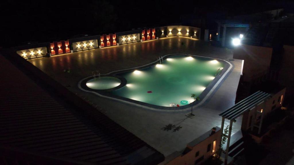 a swimming pool at night with lights around it at Infinity Hotel & Resort, Chikani , Alwar in Alwar