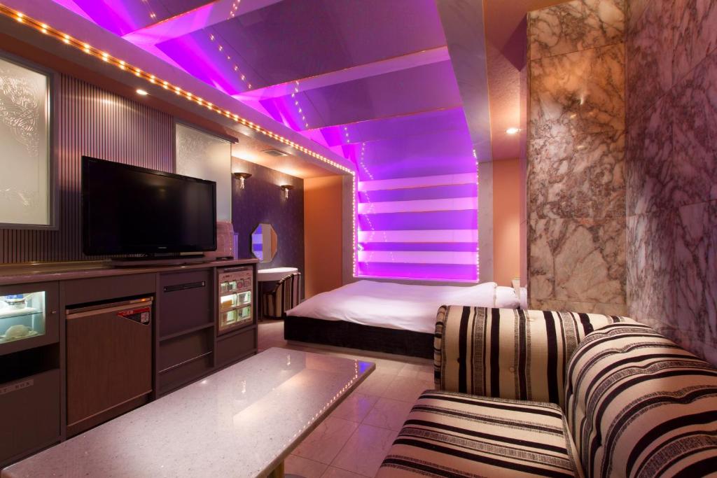 a room with a bed and a tv and purple lighting at HotelG7 in Tokyo