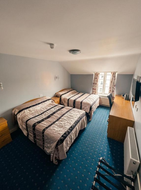 a hotel room with two beds and a television at Kilian's Lodge Hotel in Mullagh
