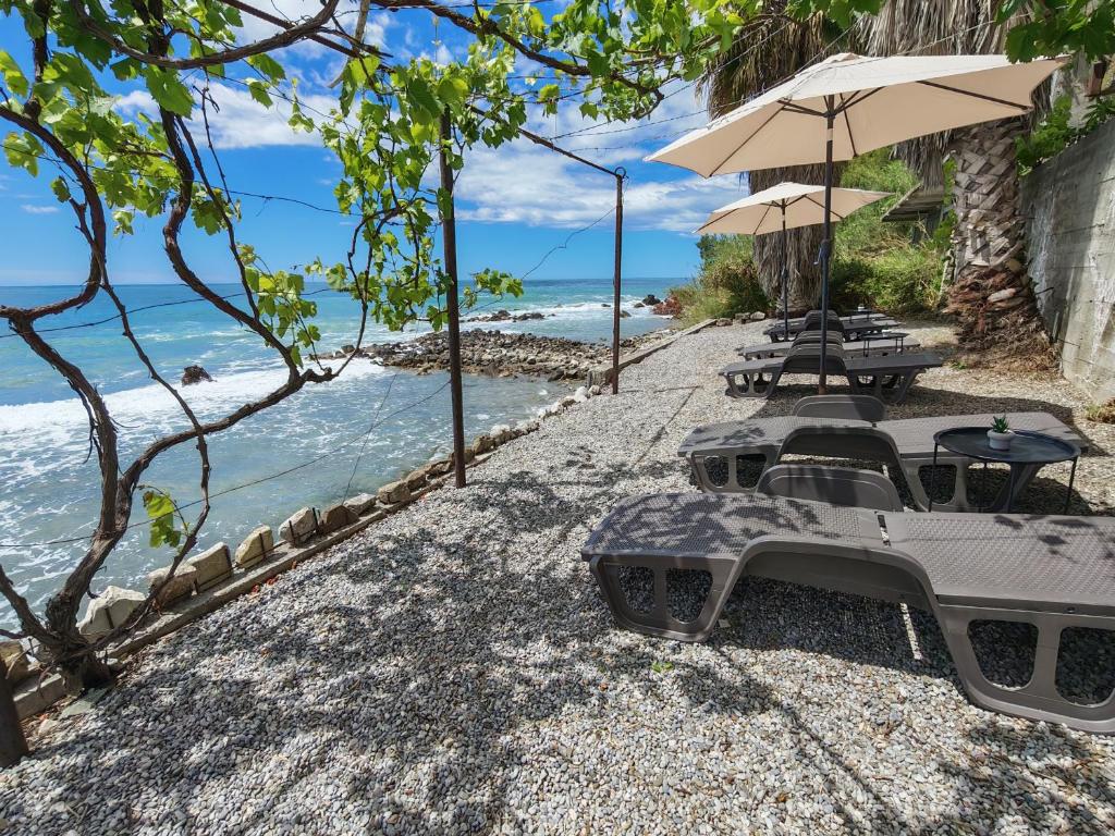 a group of chairs and umbrellas on a beach at Lana Seafront Apartments in Šušanj