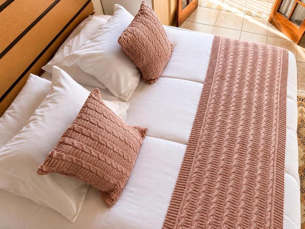a large white bed with pillows on it at Flats Morada do Jordão in Campos do Jordão