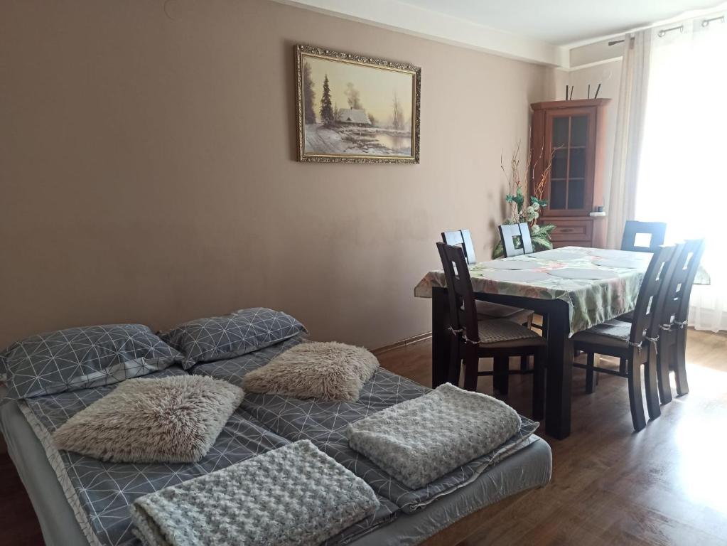 a room with a table and a bed with pillows at Apartament u Basi in Sanok