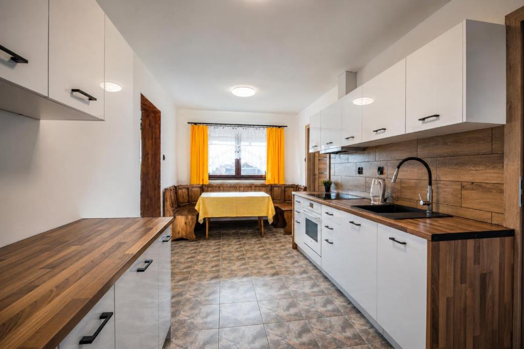 a kitchen with white cabinets and a yellow table at Apartament pod gruszą in Legbąd