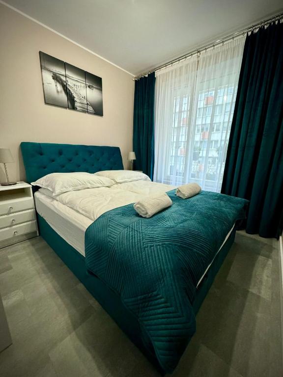 a bedroom with a bed with a blue headboard and a window at InGalaxy Green Apartment in Szczecin