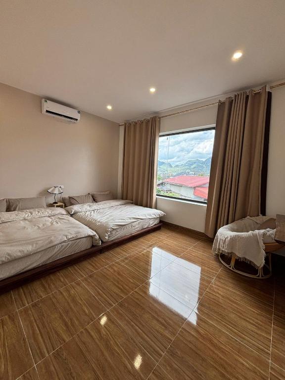 a bedroom with two beds and a large window at Lơ Mơ House in Làng Môn