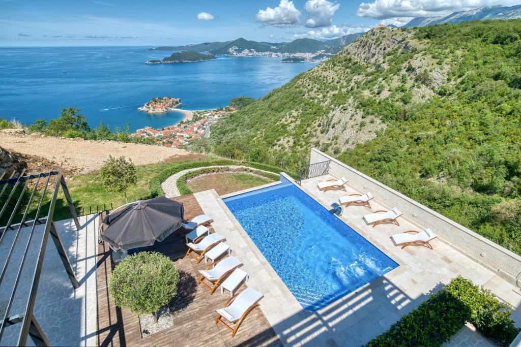 an infinity pool with chairs and a view of the ocean at Quercus Villa 2 in Blizikuće