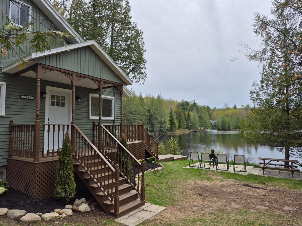 a house with a porch and stairs next to a lake at Chalet lac Chantelle in Chertsey