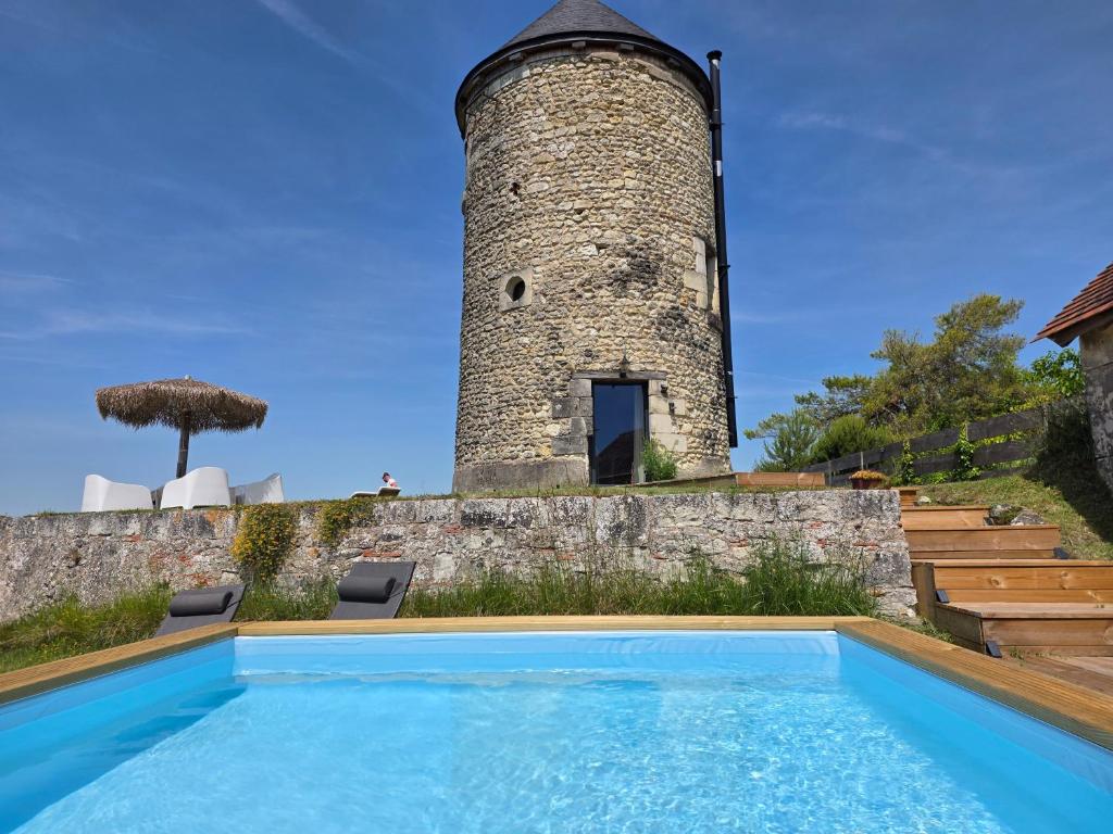 an old lighthouse sits behind a swimming pool in front of a house at Le Moulin de la Motte Baudoin in Noyers-sur-Cher