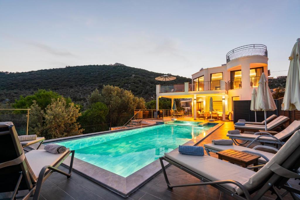 a swimming pool with chairs and a house at Villa Ekinoks in Kalkan