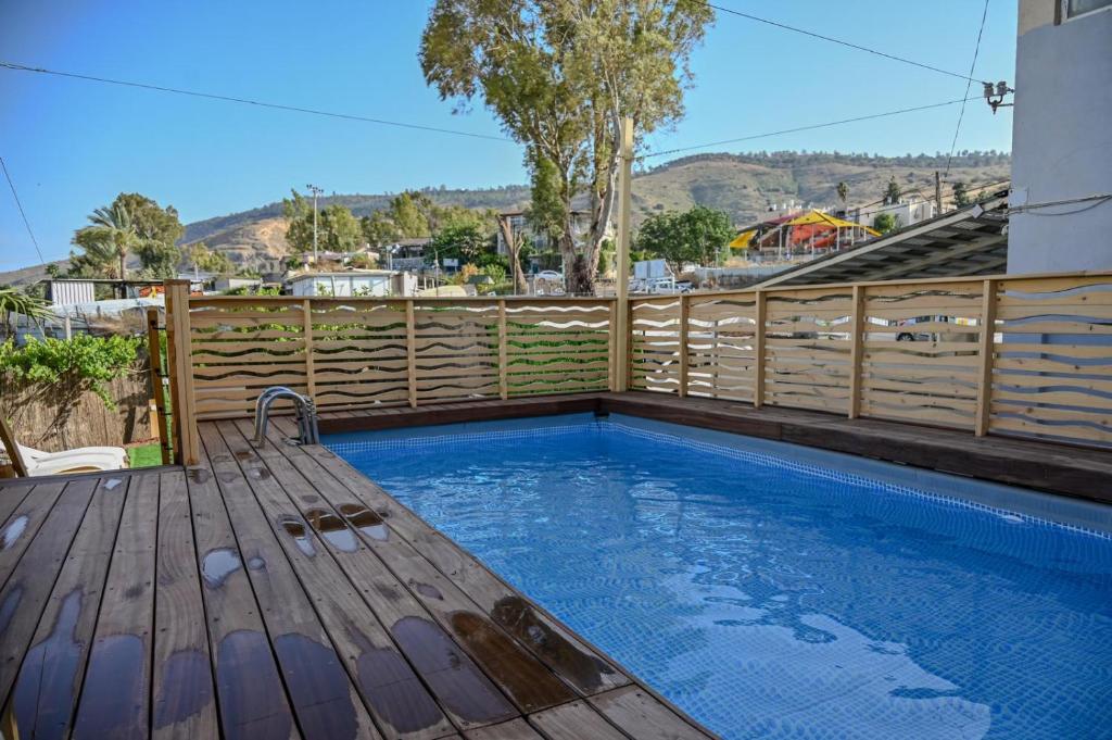a swimming pool with a wooden deck next to a fence at Domos Tiberias - Heated pool דומוס טבריה- בריכה מחוממת דקת הליכה לממד in Tiberias