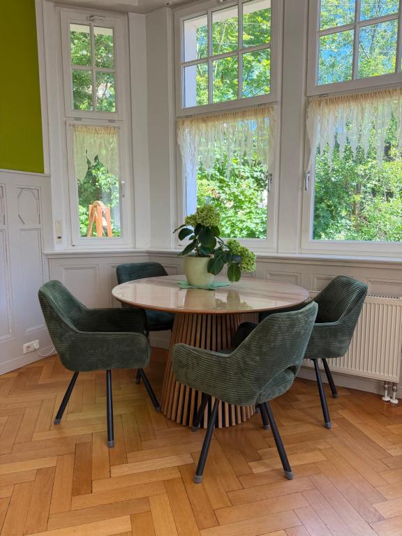 a dining room with a table and chairs and windows at Appartment im Villenviertel in Jena
