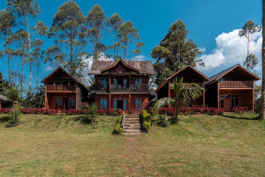 a house on a grassy field with trees at TB Villa Resort By ARBA in Palayangan