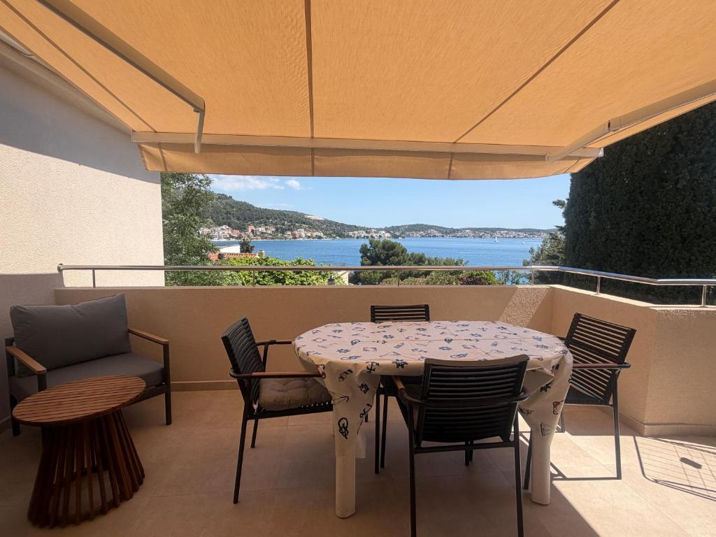 a table and chairs on a patio with a view of the ocean at Apartmani Maleš in Rogoznica