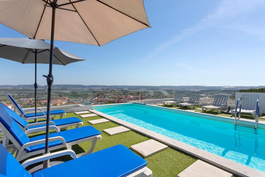 a view of a swimming pool with chairs and an umbrella at Colina do Sol 2 in Amoreira