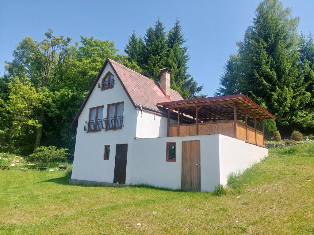 a white house with a red roof on a field at Chata Kamenice in Kamenice
