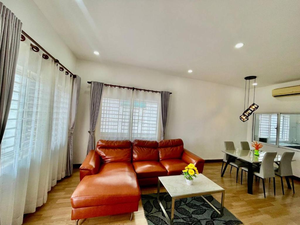 a living room with a brown leather couch and a table at Pkar Thmor Siem Reap Guest House in Phumĭ Réach Born (2)