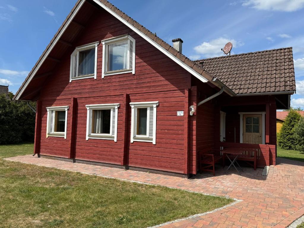 a red house with white windows and a patio at Finnische Blockhäuser in Gartow