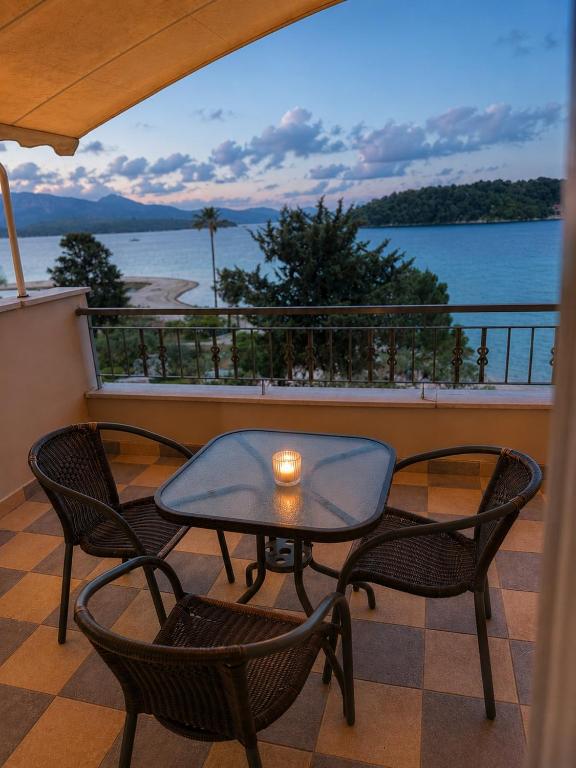 a table and chairs on a balcony with a view of the water at Akrogiali Studios - Nidri, Lefkada in Nydri