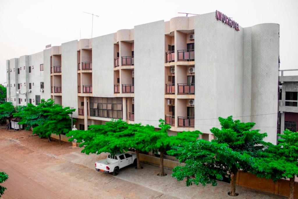 a building with a white van parked in front of it at NIF-UR Hotel Bohicon in Bohicon