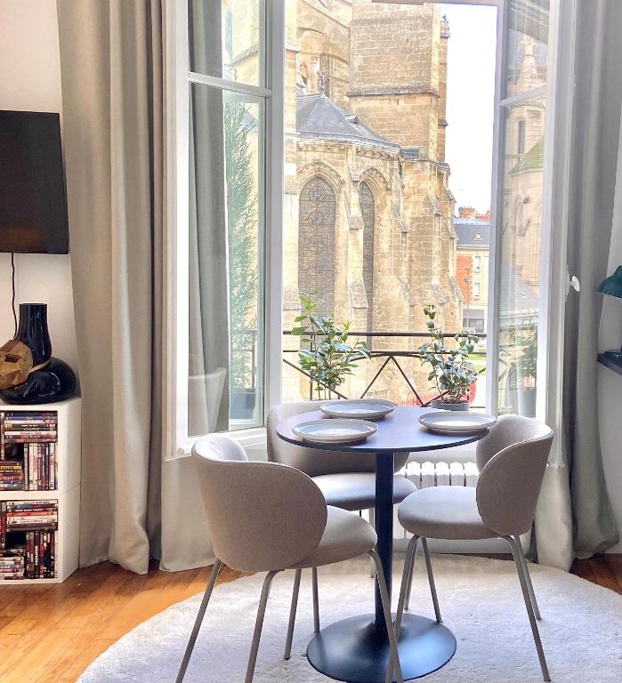 a dining room with a table and chairs in front of a window at La Cathédrale in Soissons