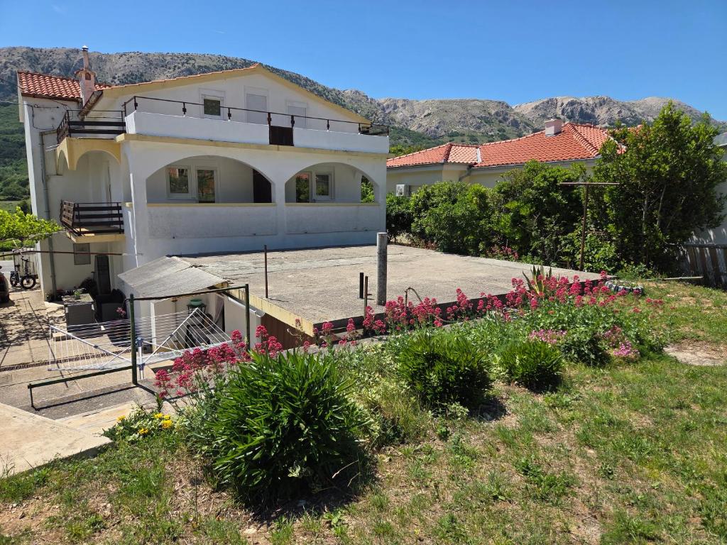 a house with a lot of flowers in the yard at Apartments Drita in Baška