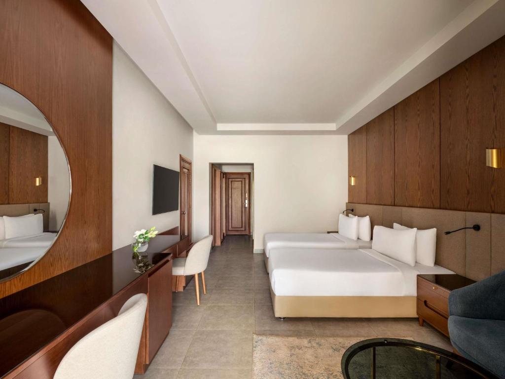 a hotel room with two beds and a couch at Mövenpick Hotel Cairo - Media City in 6th Of October