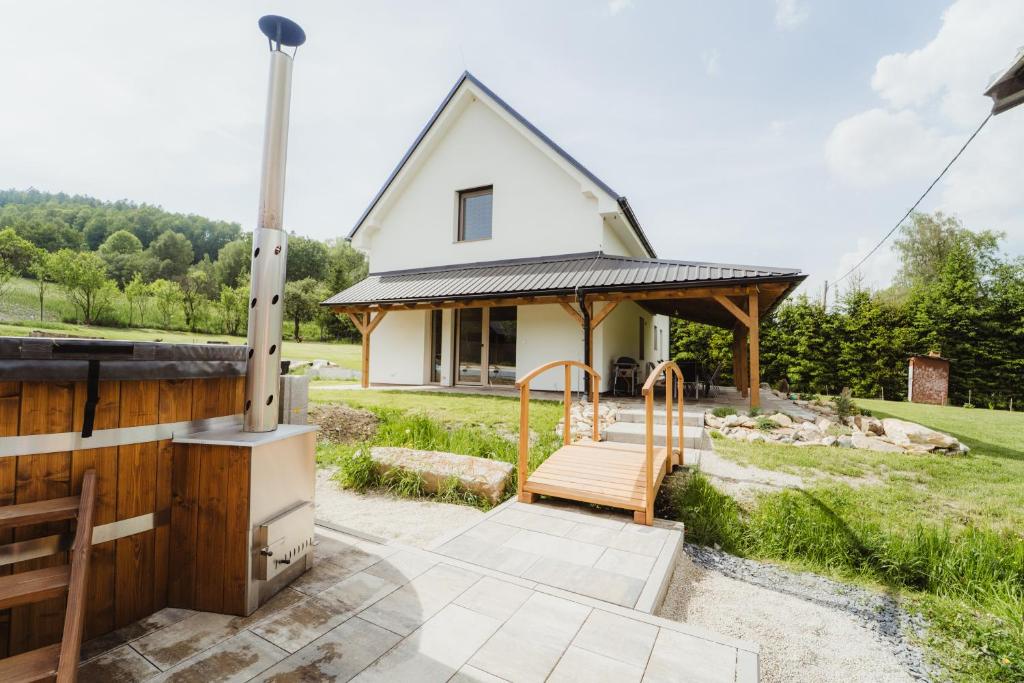 a small white house with a porch and a stove at Prázdninový dům Sobotín in Sobotín