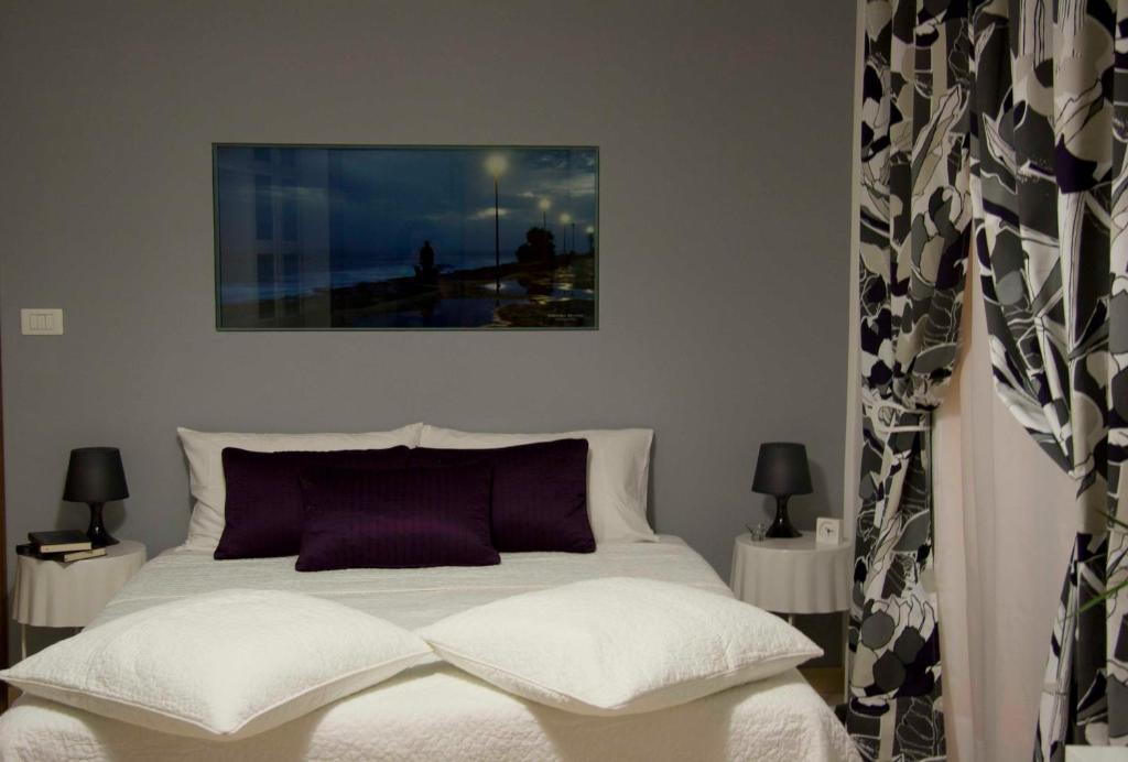 ein Schlafzimmer mit einem weißen Bett mit lila Kissen in der Unterkunft Modica Suite in Modica