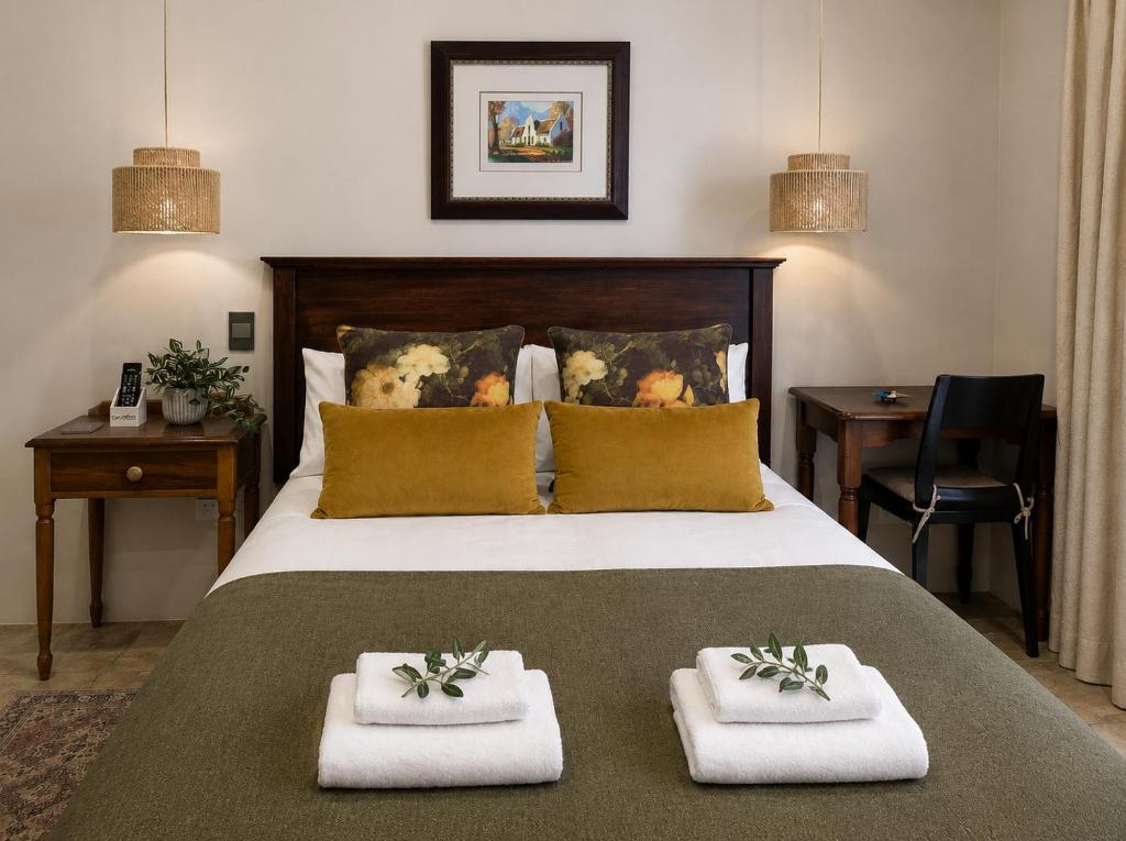 a bedroom with a large bed with two towels at Alimento Guest House in Upington