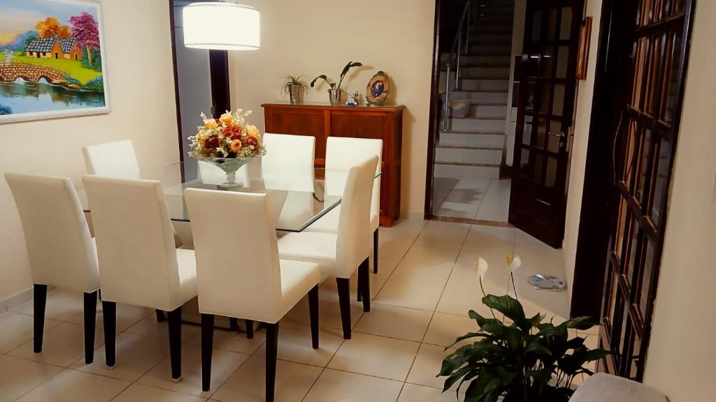 a dining room with a glass table and white chairs at Casa Cris e Edinho in Garanhuns
