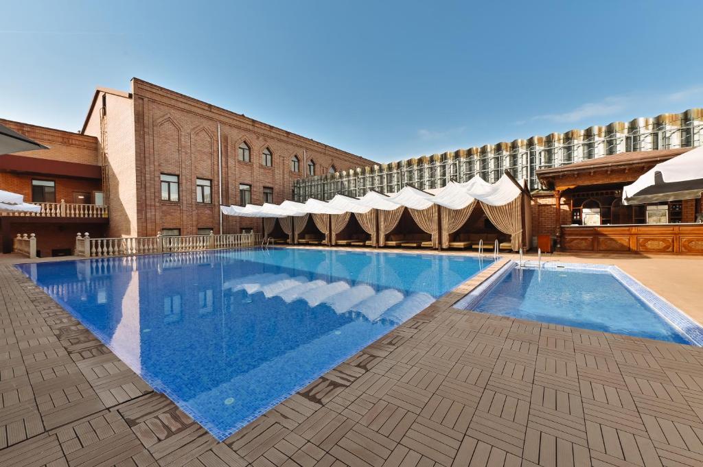 a large swimming pool in front of a building at Ichan Qal'a Premium Class Hotel in Tashkent