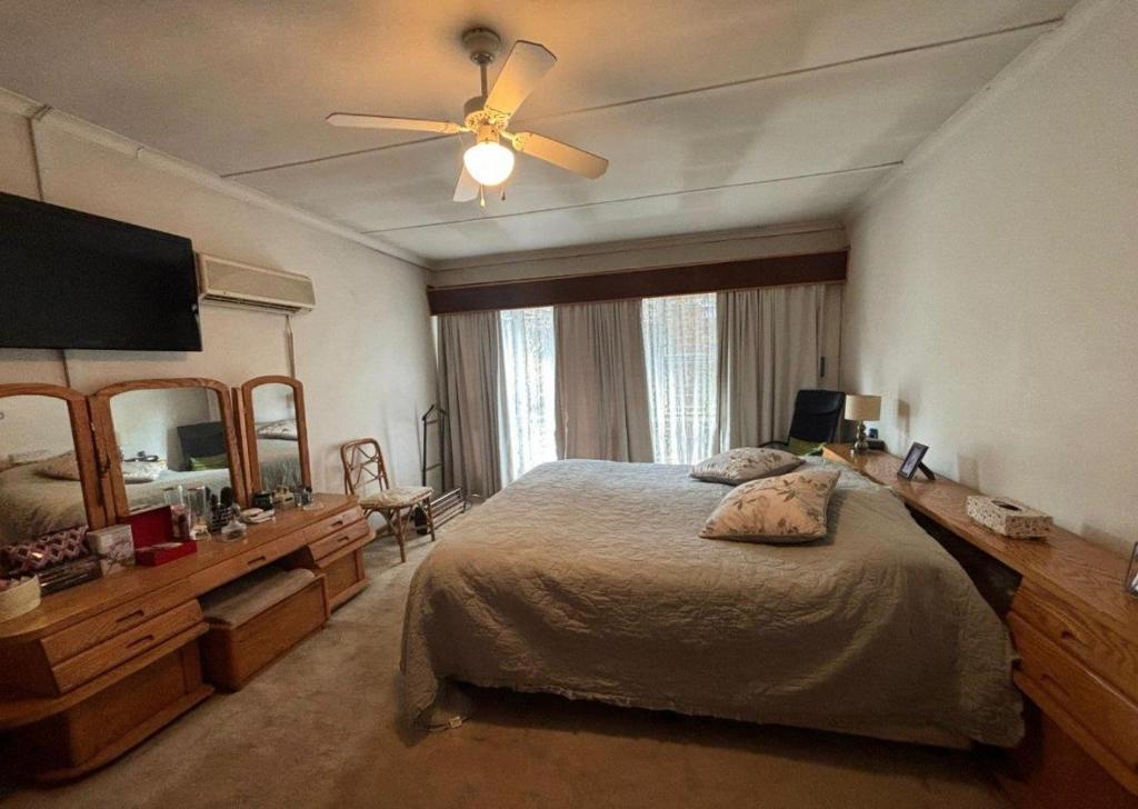 a bedroom with a bed and a ceiling fan at Wageney2us in Kempton Park