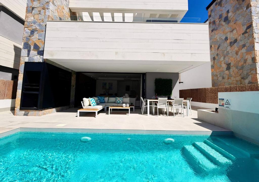 a swimming pool in front of a house at LUXURY VILLA ALMENDRO 15 WITH PRIVATE HEATED POOL at SANTA ROSALIA RESORT by PREMIUM SPAIN PROPERTIES in Torre-Pacheco