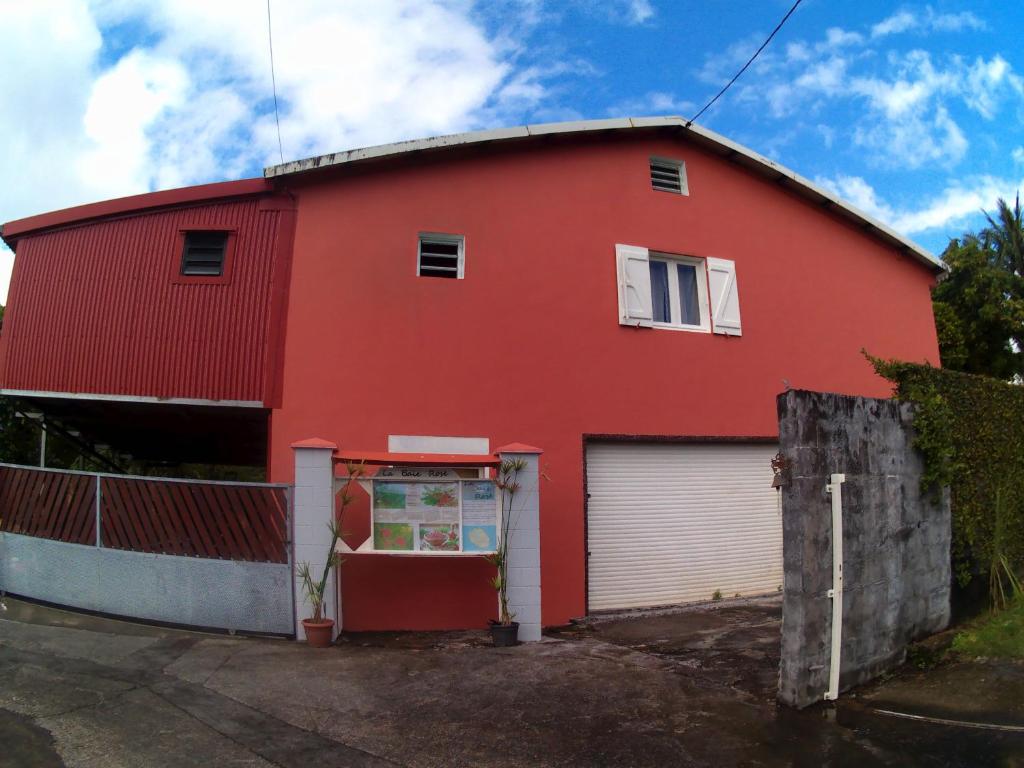 a red house with a garage at La baie rose in Sainte-Rose