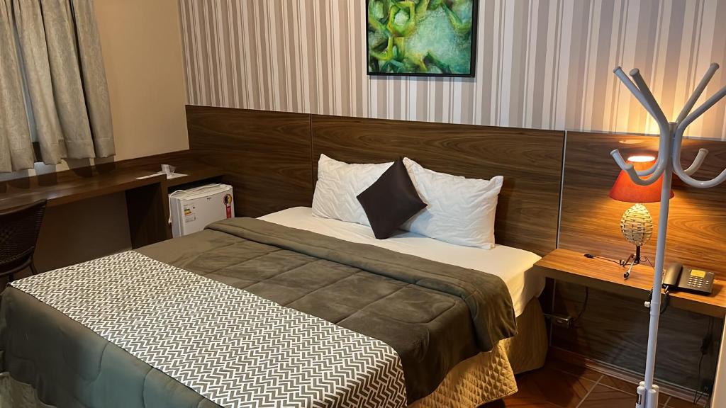 a hotel room with a bed and a lamp at Ibitur Hotel in Ibiúna